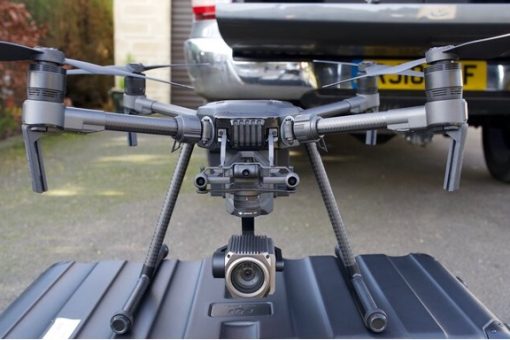 A black top inspection drone sat on a case in a driveway.