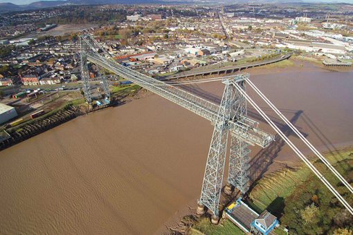 An aerial drone shot of a bridge being built over a river, with the city in the landscape. This was taken during a RUAS building survey.
