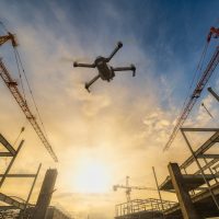 A drone flying over a construction site with a sunset.
