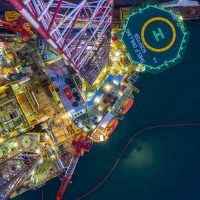 An aerial drone shot of an offshore oil rig drilling platform at night.
