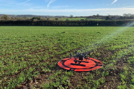 A drone in a field, preparing to take off and produce a topographical survey.