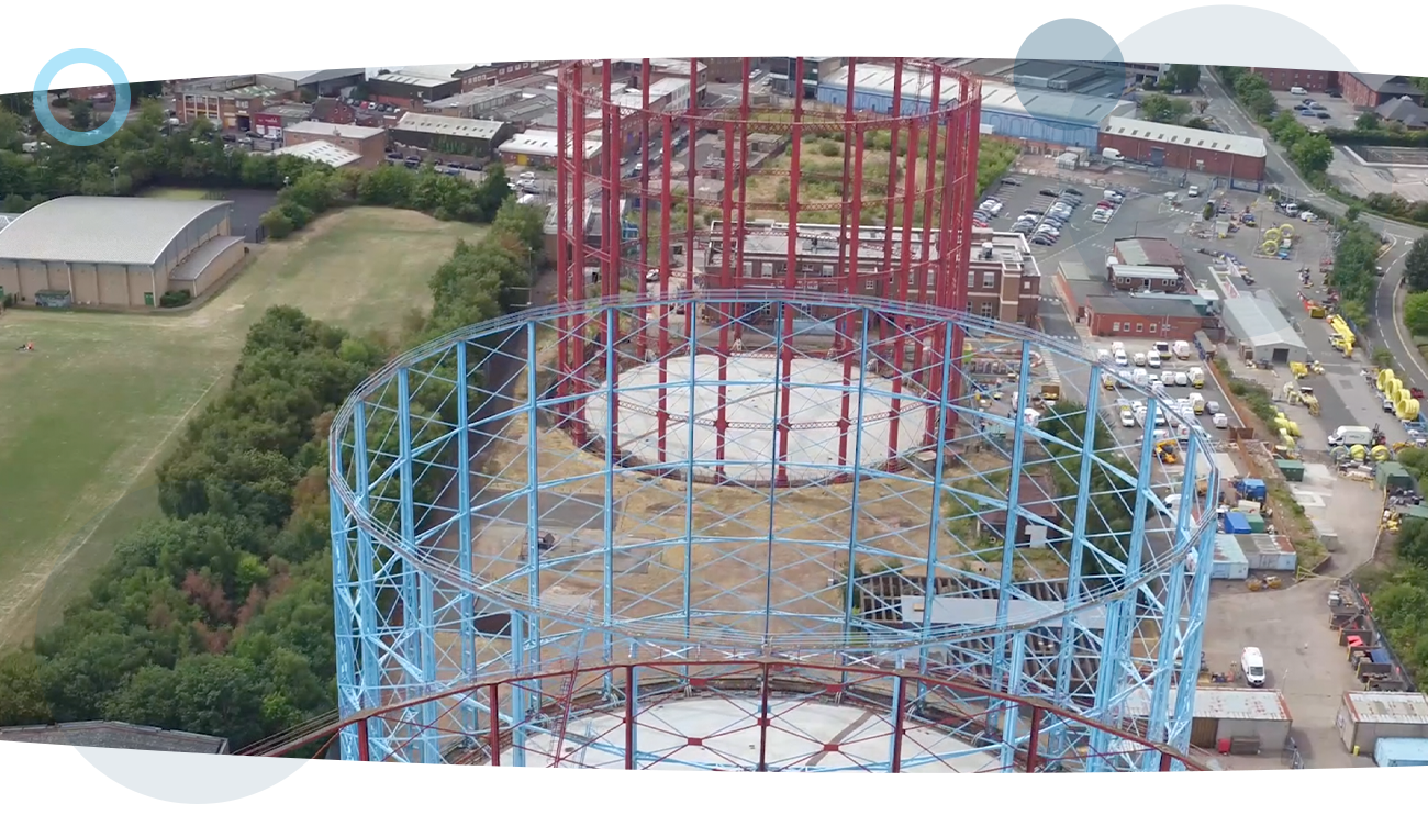 A drone shot of gas holders with industrial buildings behind it, during a gas inspection run by a RUAS trained drone pilot.