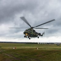 Military helicopter takes off from a grass field in the background of the city