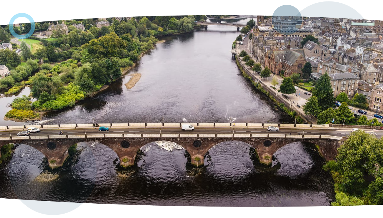 A drone shot of a river running under a bridge, with two cities either side, captured during a RUAS oil and gas inspection.