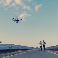 Engineers inspecting solar panels at a solar power plant using drone services.