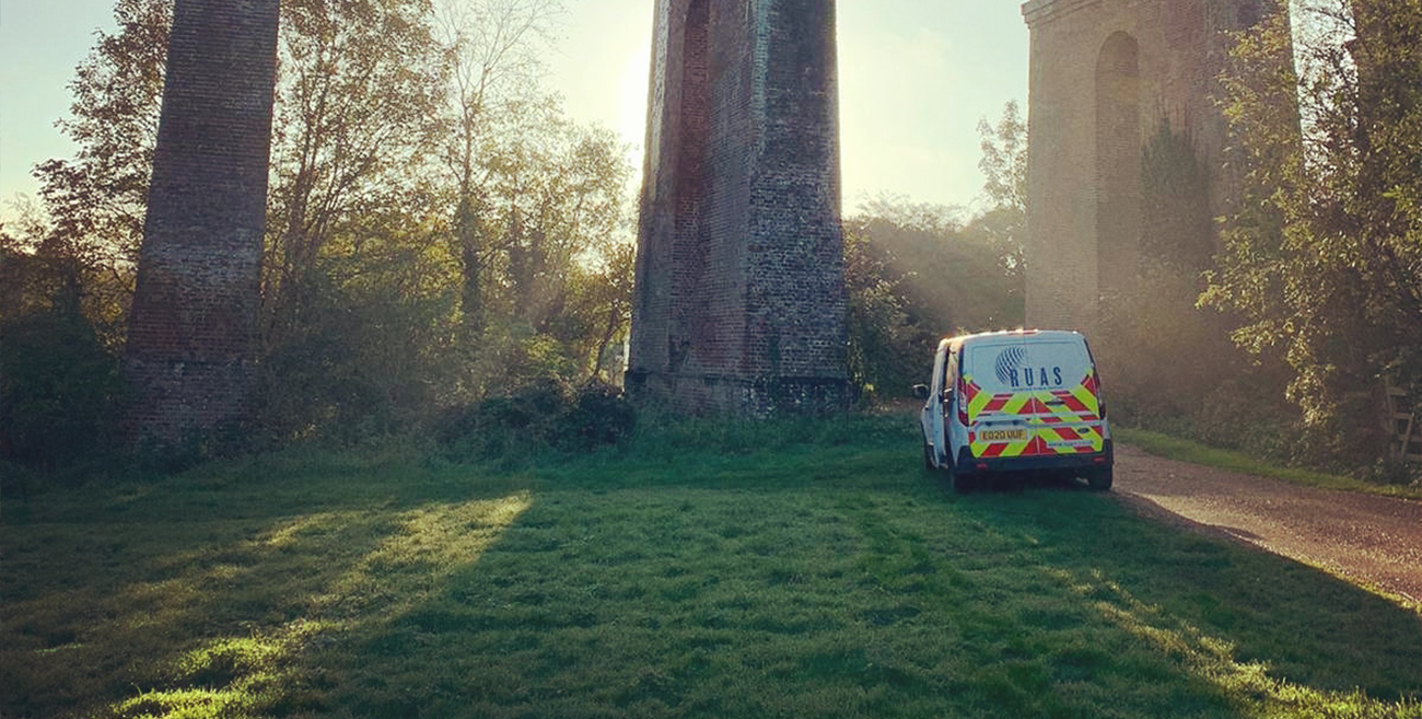 A RUAS van parked underneath a bridge with the sun setting behind the bridge pillar.