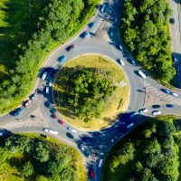 Composite aerial image of traffic using a small roundabout with multiple connecting roads.