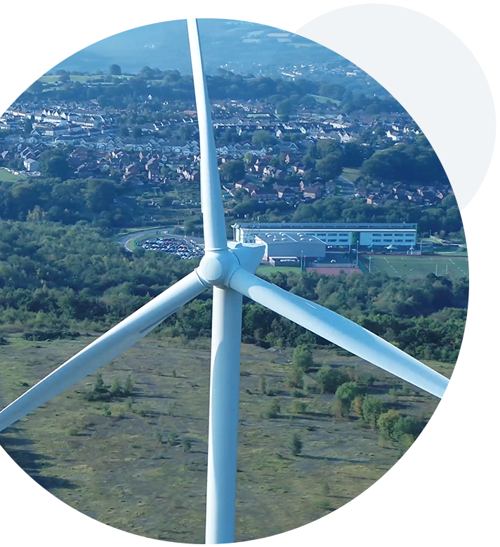 A circular image of a wind turbine producing power in a field.