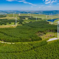 An aerial drone panorama shot of turbines at a large onshore wind farm in Wales.