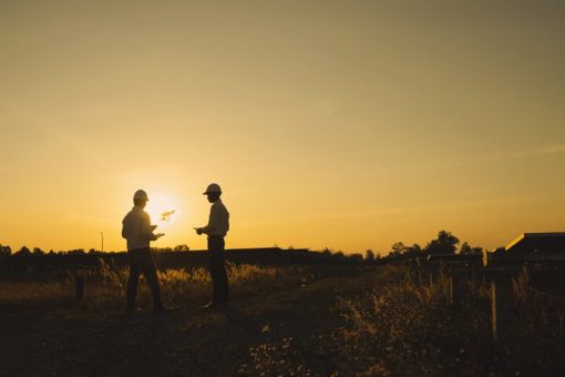 Two men controlling a drone using a drone radio transmitter the sunset for a promotional video.