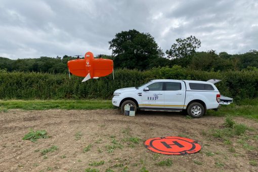 A drone taking off in the middle of a field with a RUAS truck in the back. This depicts the difference of VLOS, EVLOS and BVLOS.