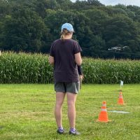 Three people in the middle of a field flying a drone during their training course.